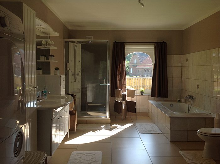 Ruime badkamer met bad, douche en wasmachine