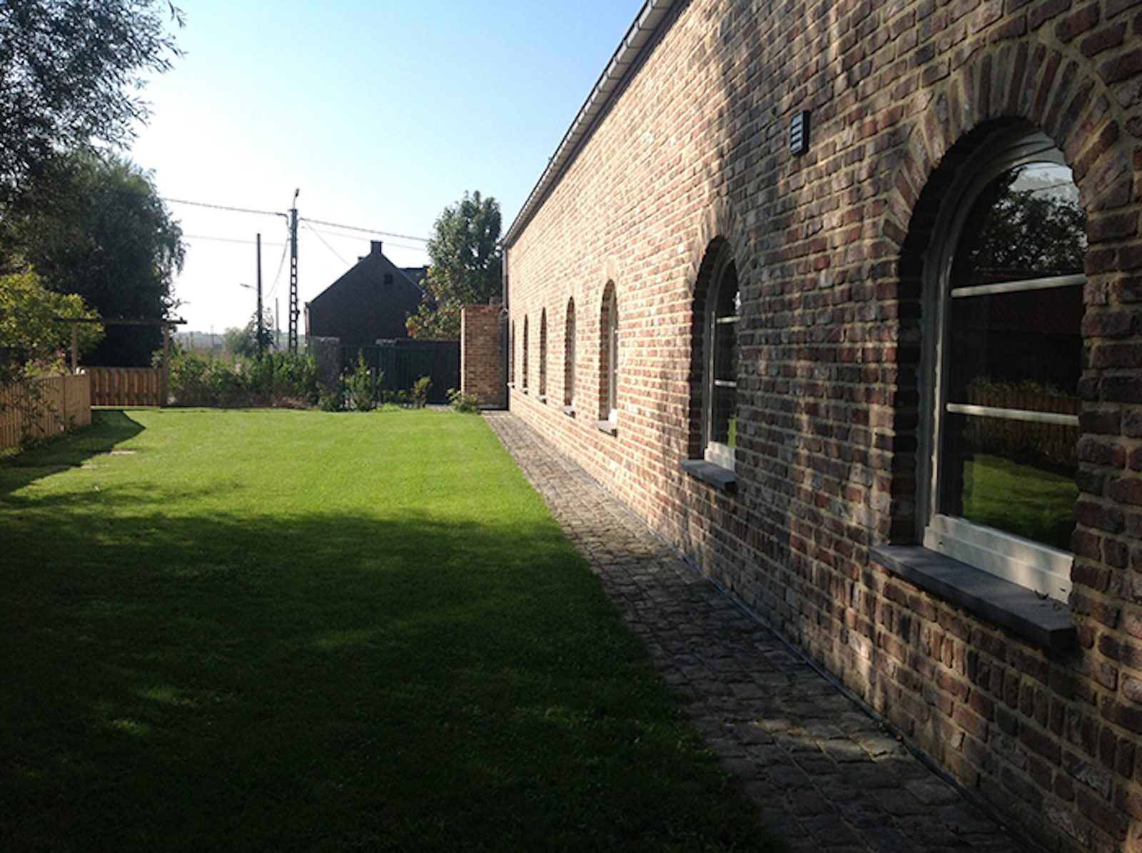 Lange bakstenen hoeve met boogramen en grasperk